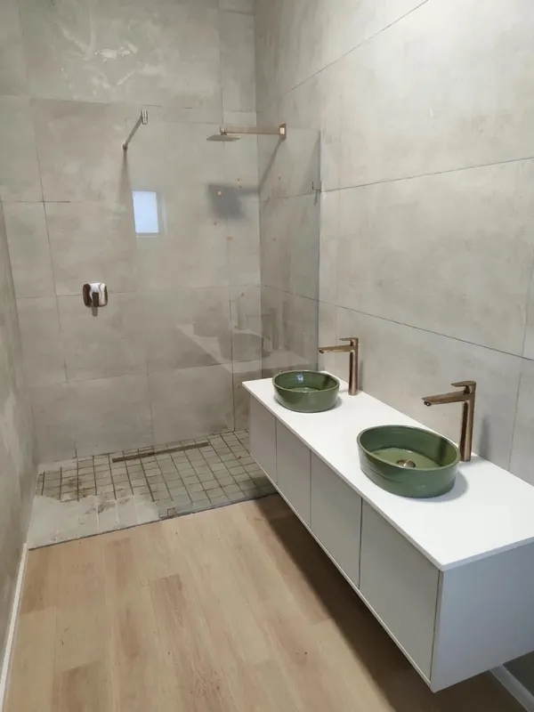 Double vessel basins with brass taps and walk-in shower with linear drain