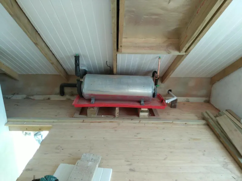 Horizontal geyser on a drip tray in a roof space with insulated pipework